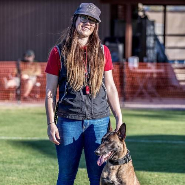 Woman and German Shepherd dog standing on a sports field.