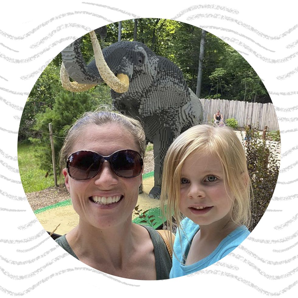 Woman and young girl smiling with a large elephant statue in the background.